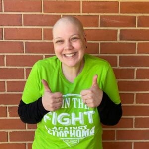 Woman showing two thumbs up signs after finishing treatment for lymphoma.