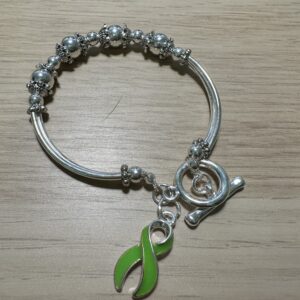 Image of silver bracelet with baubles and a green lymphoma ribbon